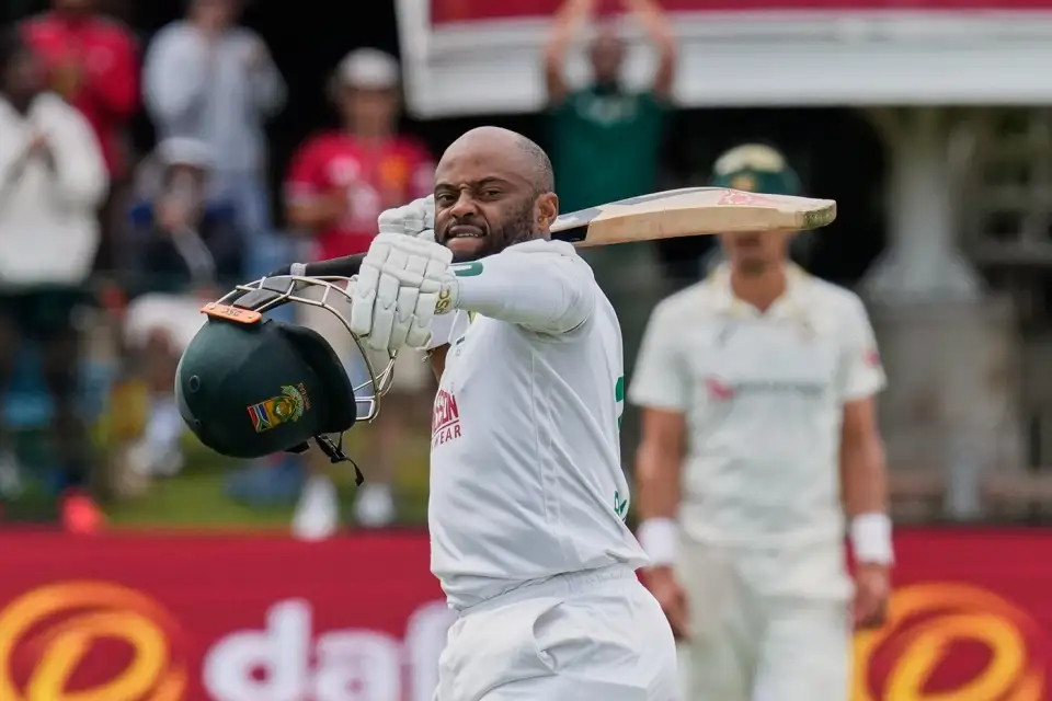 South African captain Temba Bavuma raises his bat and helmet celebrating a resilient century in the Test match against Australia